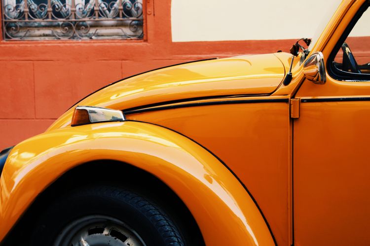 Close-up of vintage car parked against orange wall