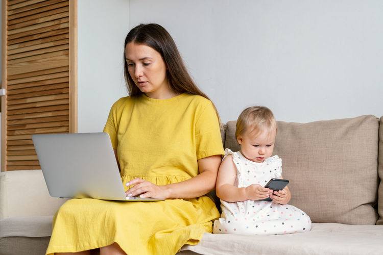 Unplugging mother after work. child using mobile phone while mom working remotly at home