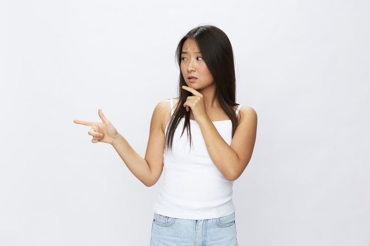 Portrait of young woman standing against white background