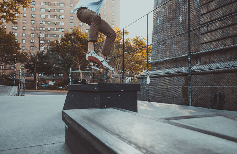 Low section of man skateboarding at skating park against building
