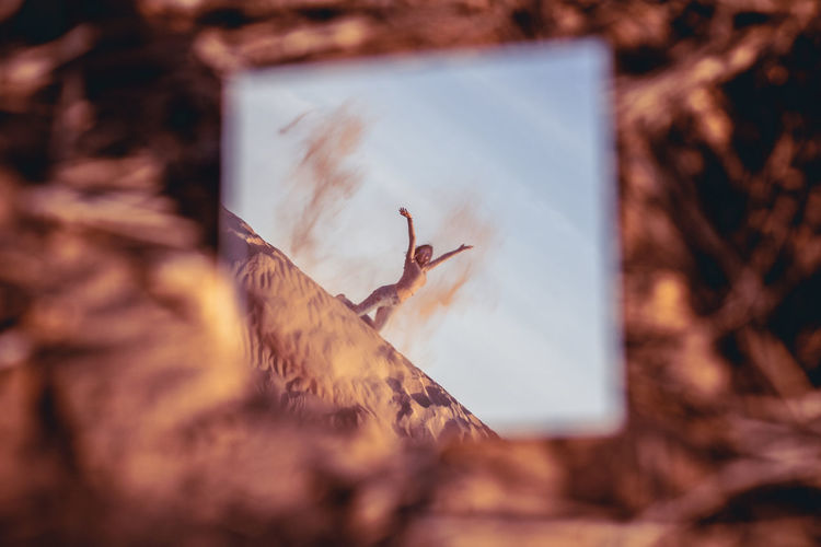 Reflection of woman spilling sand in mirror