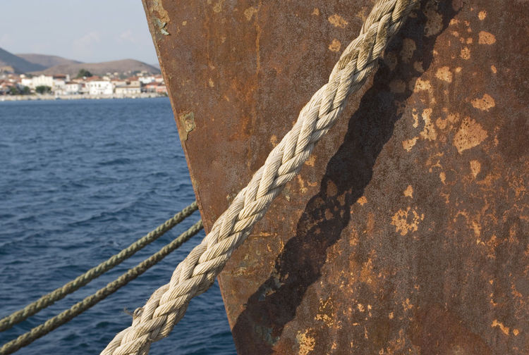 Close-up of rope tied to bollard by sea