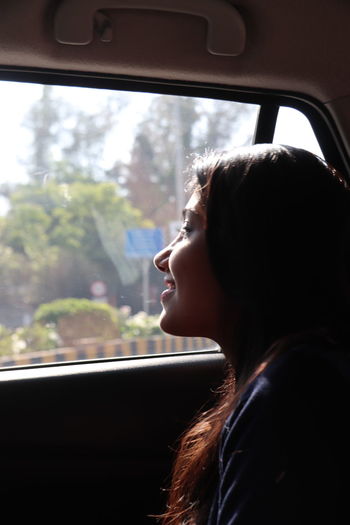 Woman looking away through window in car