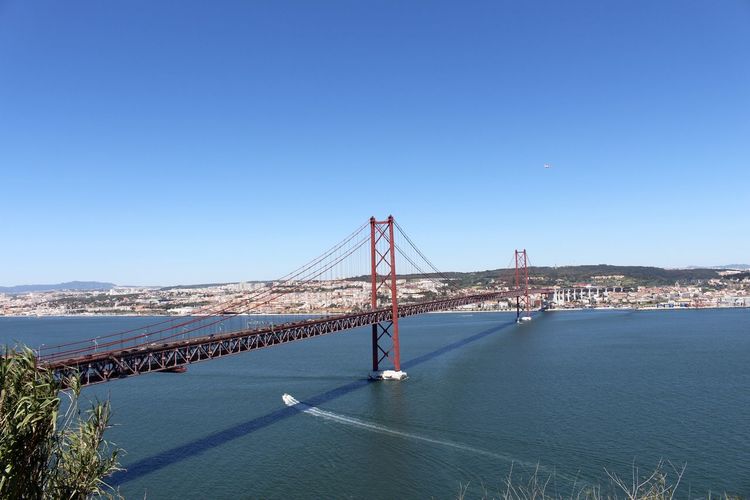 Suspension bridge over sea against blue sky