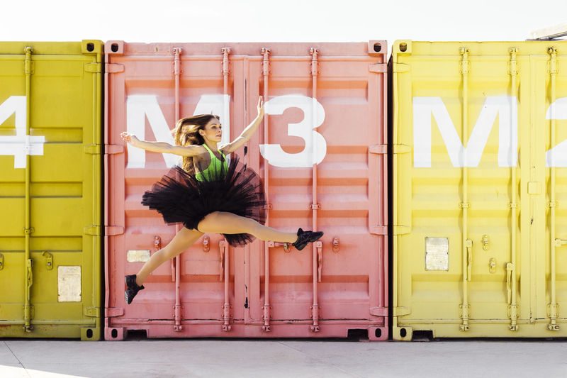 Ballet dancer dancing against cargo containers