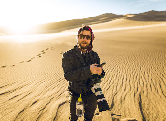Portrait of hiker holding smart phone while standing at great sand dunes national park