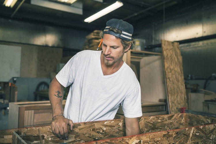 Carpenter holding wooden plank at workshop