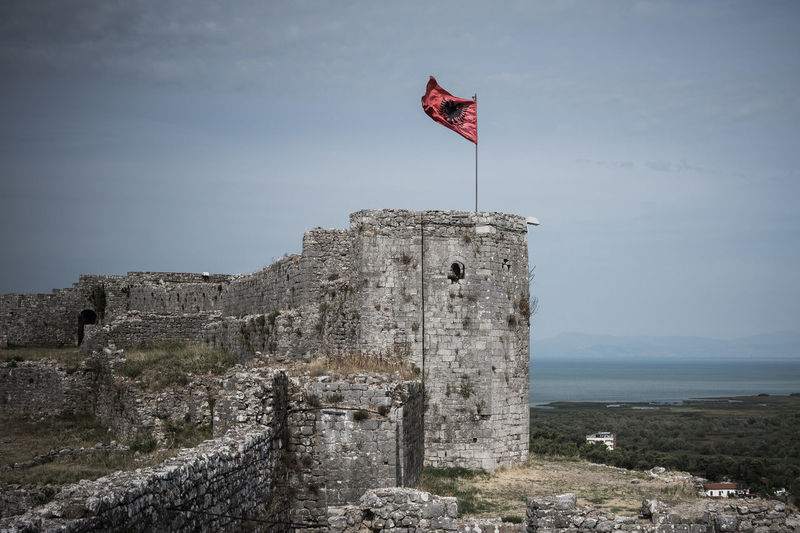 Low angle view of albanian flag on old ruin against sky