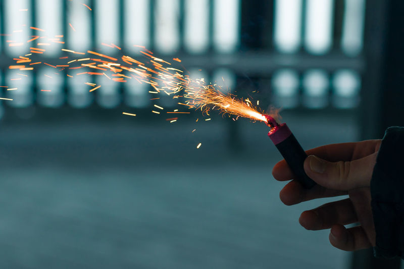 Burning firecracker with sparks. guy holding a petard in a hand