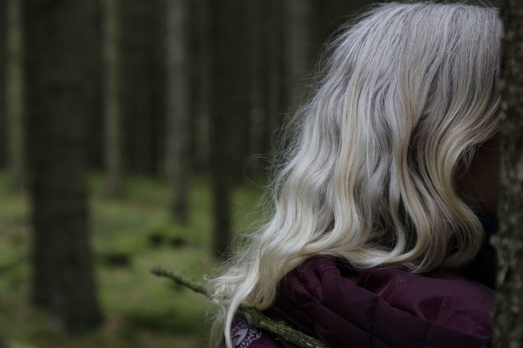 Rear view of blond haired woman in forest close to the back head 