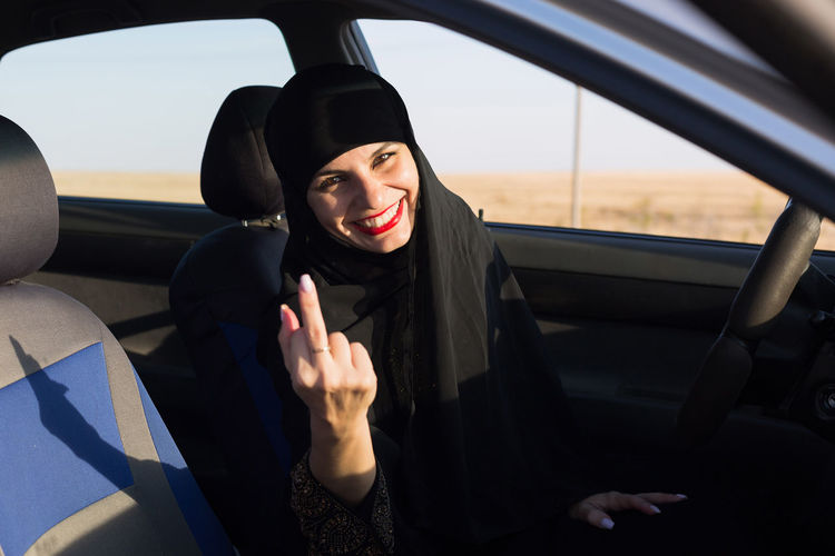 Portrait of woman in hijab gesturing while sitting in car