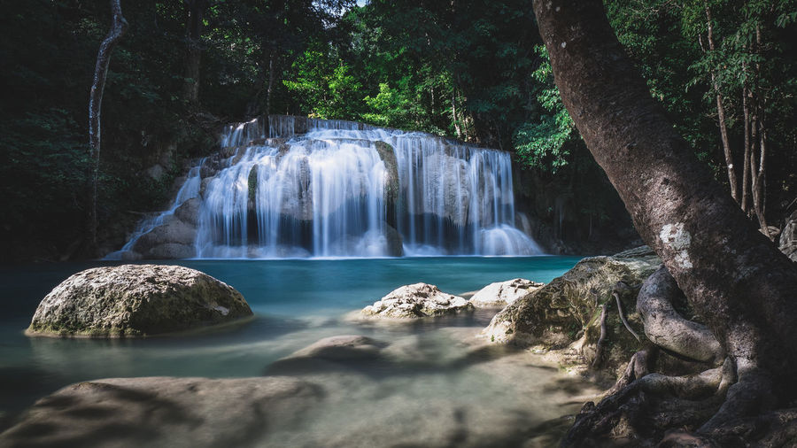 Scenic view of waterfall smooth flowing water in rainforest. erawan falls, kanchanaburi, thailand.