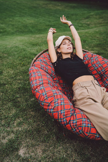 Young woman relaxing on chair over grass