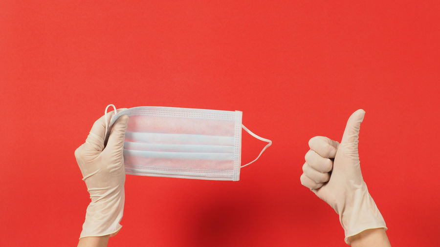 Close-up of hand holding red over colored background