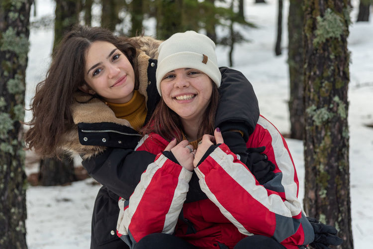 Portrait of smiling friend  women hugging  in snow