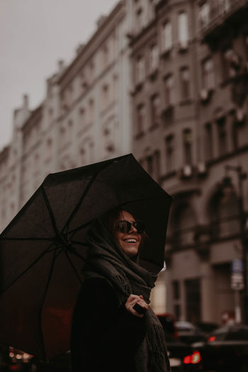Rear view of woman with umbrella standing in city