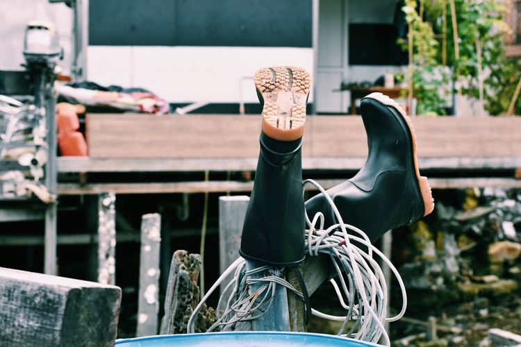Rubber boots and cable on wooden post