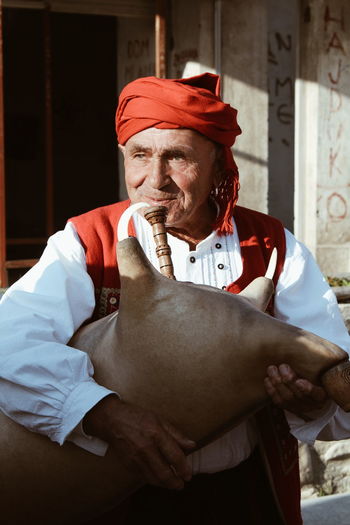 Senior man wearing traditional clothing holding musical instrument outdoors