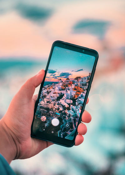 Cropped hand of person photographing town with mobile phone