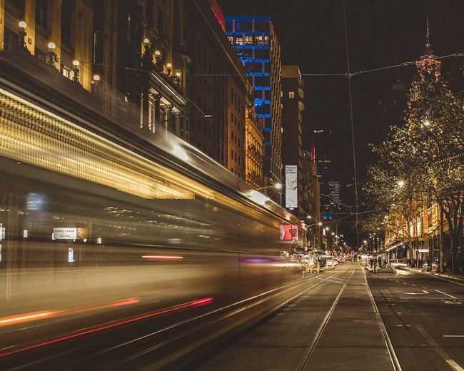 Light trails on road amidst buildings in city at night