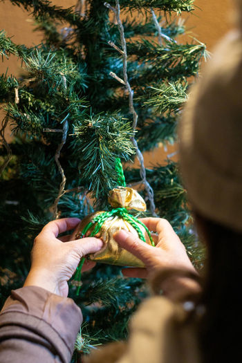 Adult woman decorating christmas tree with sacks of gold fabric