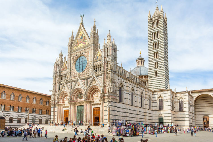 Duomo di siena cathedral with tourists in the piazza