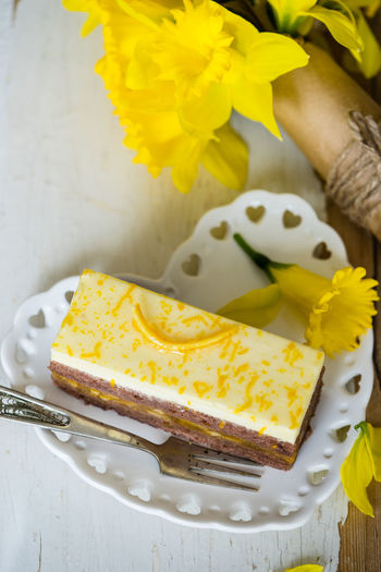 High angle view of lemon cake and daffodils in heart shaped plate