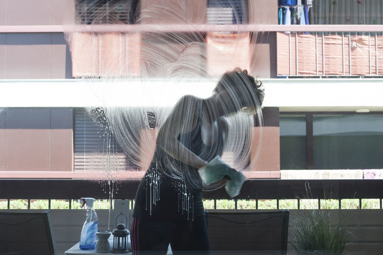 Woman cleaning glass wall at home