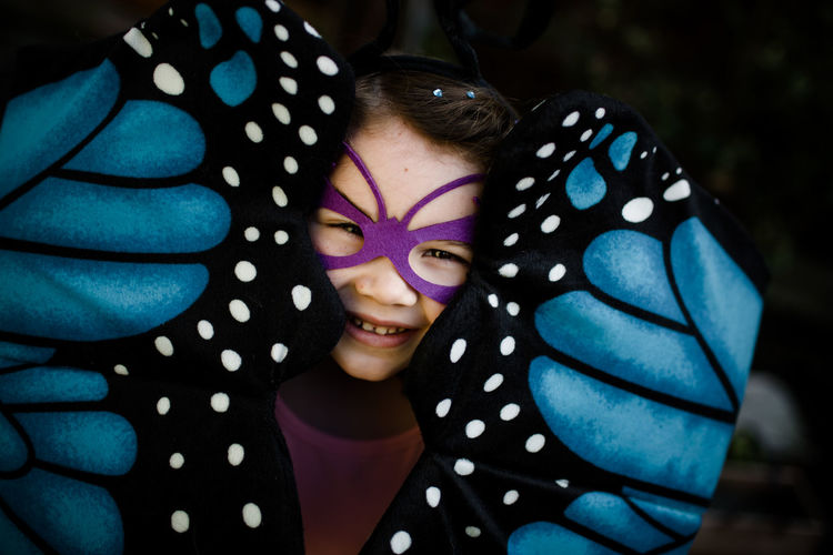 Young girl in dress up peaking out from butterfly wings