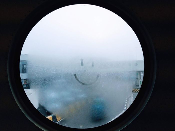 Airport tarmac seen through foggy airport window with a smiley drawn on it