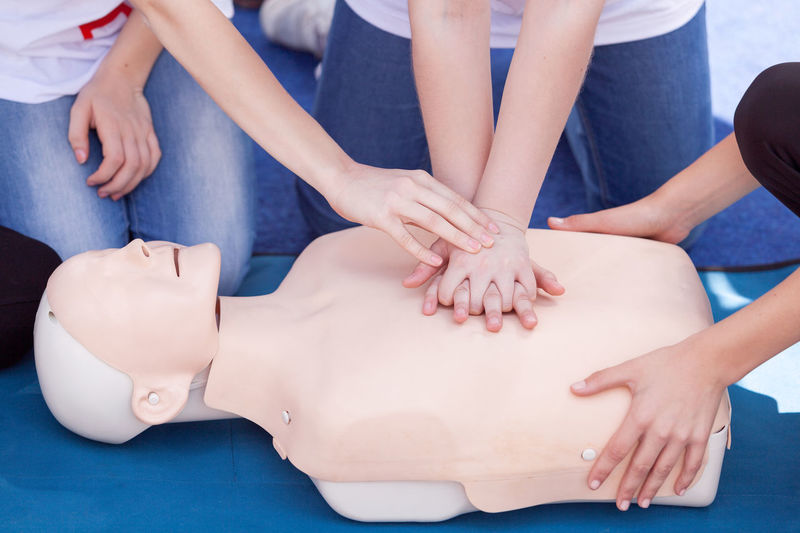 Midsection of paramedics performing cpr on mannequin