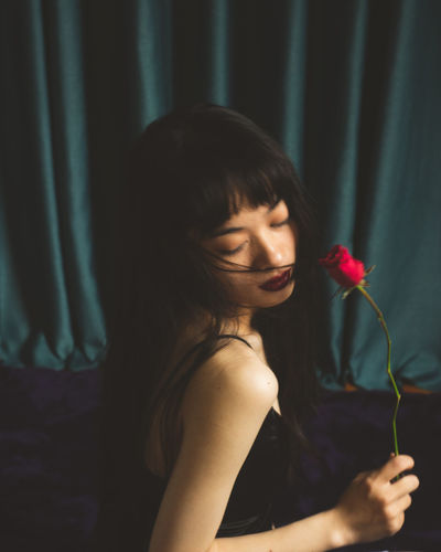 Close-up of young woman holding red rose