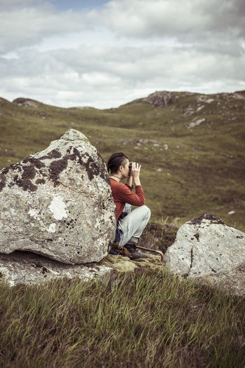 Girl leans on rock with binoculars