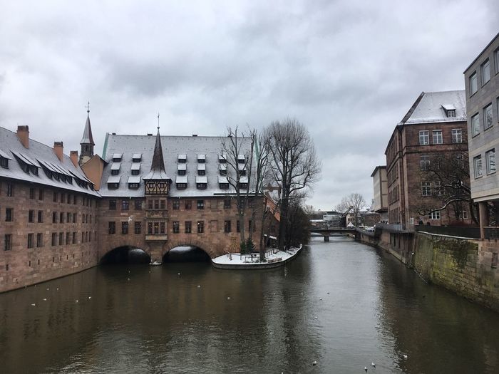 River passing through city against cloudy sky