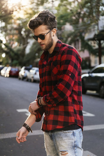 Man wearing plaid shirt and sunglasses while standing on road