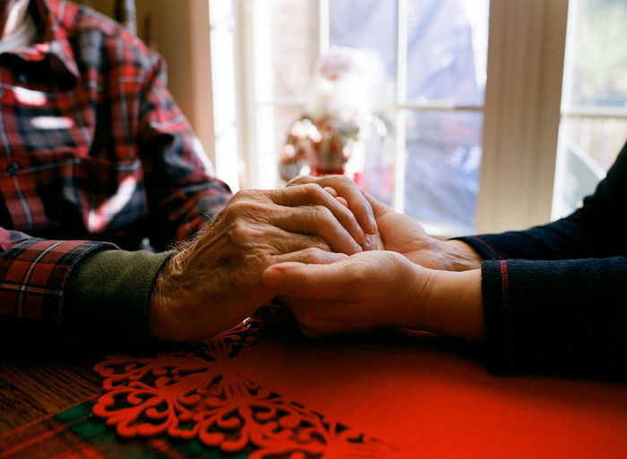 Daughter holding father's aged hands. comforting and warming