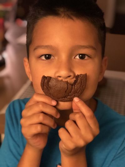 Close-up portrait of boy holding cookie over mouth