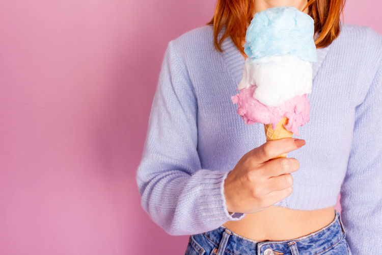 Midsection of woman holding ice cream against wall