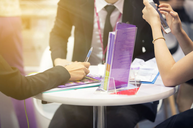 Midsection of businesspeople brainstorming on desk at office