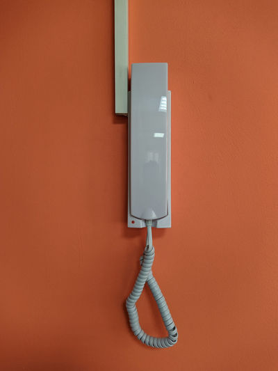 Close-up of electric lamp against orange wall