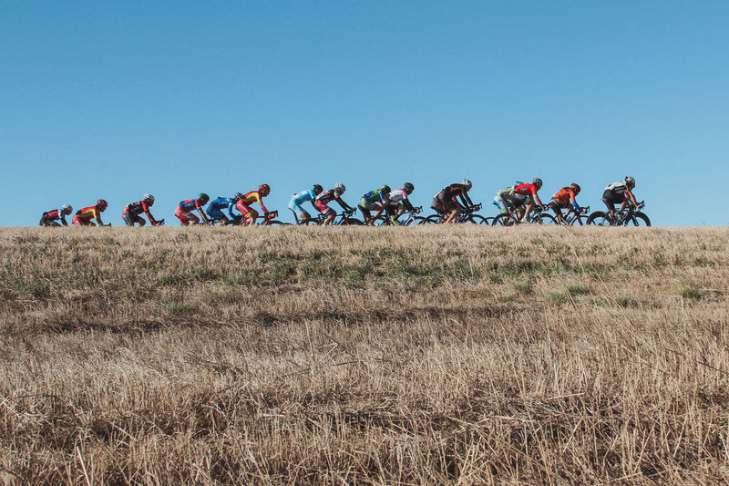 Cyclists performing during sports race against clear blue sky