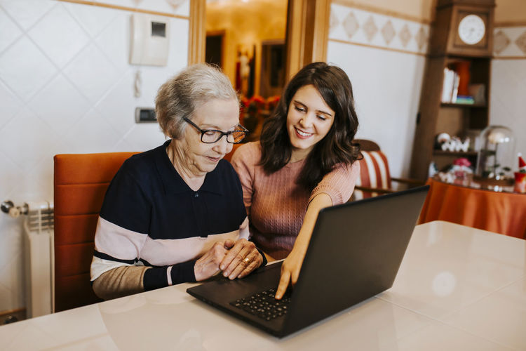Granddaughter teaching her grandmother something on the laptop