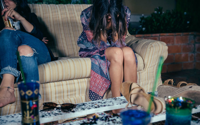 Drunk woman leaning on sofa during party in backyard at night