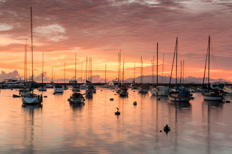 Boats moored on sea against sky during sunset