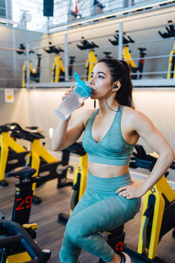 Portrait of young woman drinking water in gym