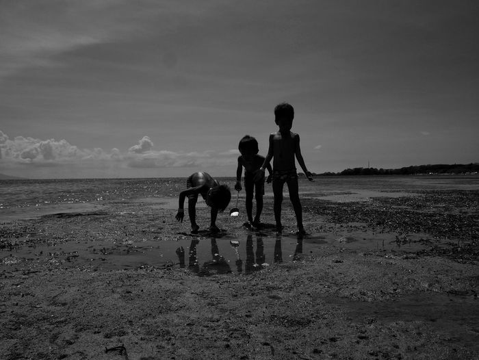 Children playing on beach against sky