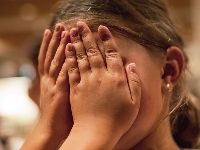 Portrait of a girl covering her face with her hands