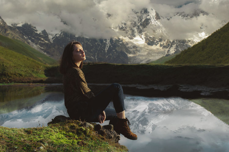 Side view of woman standing on snowcapped mountain