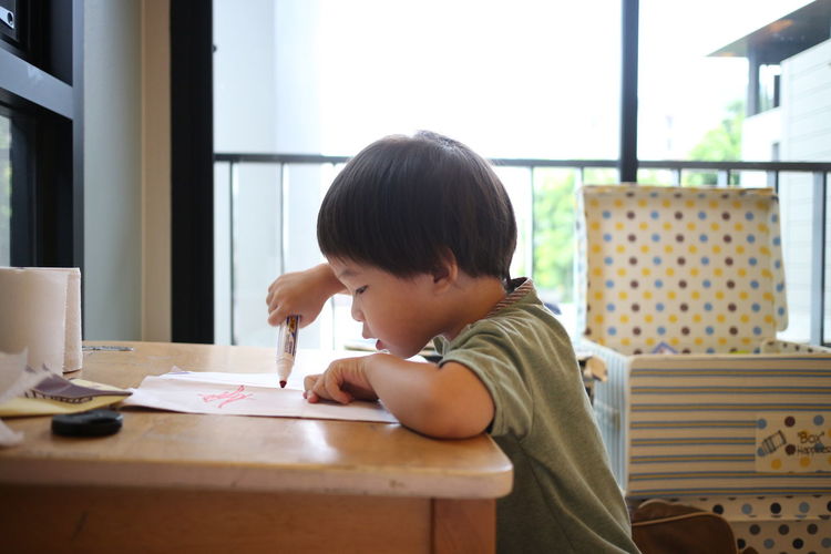 Boy sitting by table at home