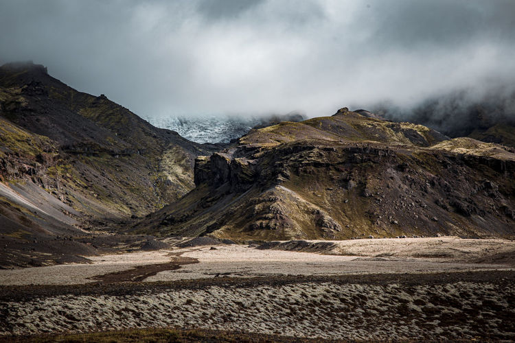 Volcanic landscape in iceland with the skaftafell glacier hiding behind a curtain of clouds.